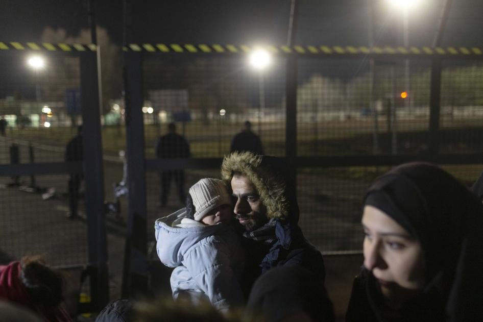 A man holds a child close to a border crossing between Serbia and Hungary, Kelebija, Serbia, Thursday, February 2020. 