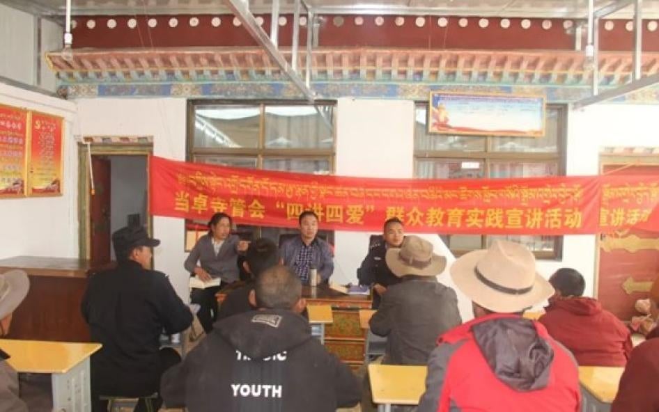 Three people lead a meeting while sitting in front of a banner written in Chinese letters