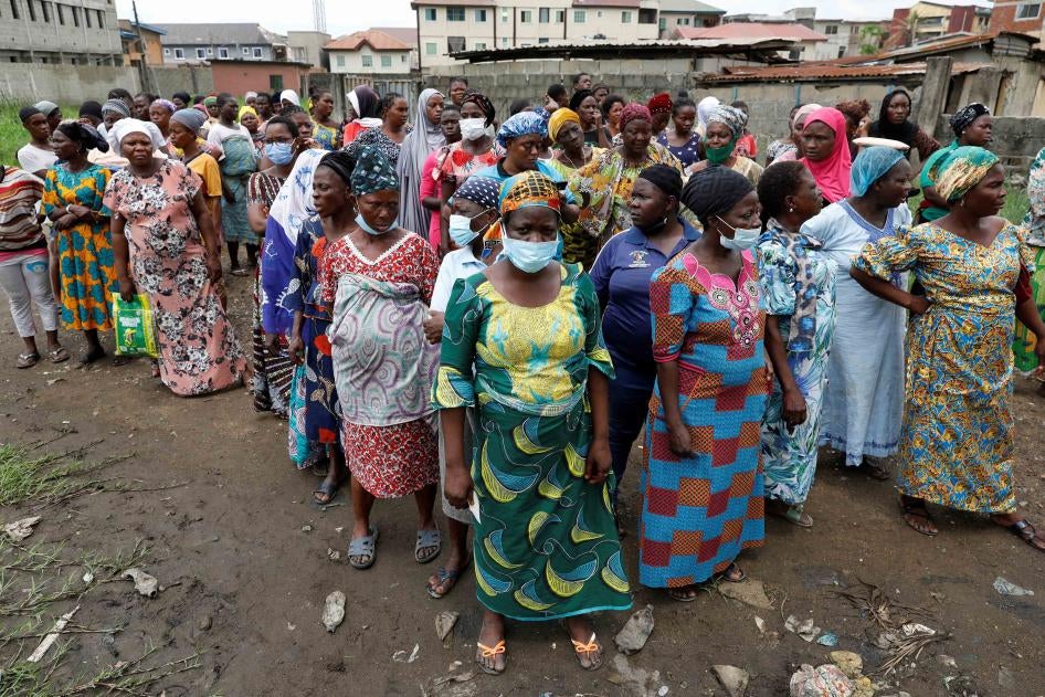 Des femmes nigérianes faisaient la queue pour recevoir des paquets de nourriture distribués par des volontaires de l’ONG Lagos Food Bank Initiative, dans le quartier de Oworoshoki, dans la banlieue de Lagos au Nigeria, le 10 juillet 2021.
