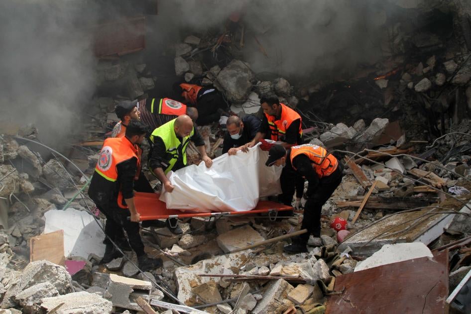 Members of the Palestinian civil defense remove the body of one of the 44 civilians killed after three multi-story residential buildings collapsed as a result of Israeli airstrikes in central Gaza City