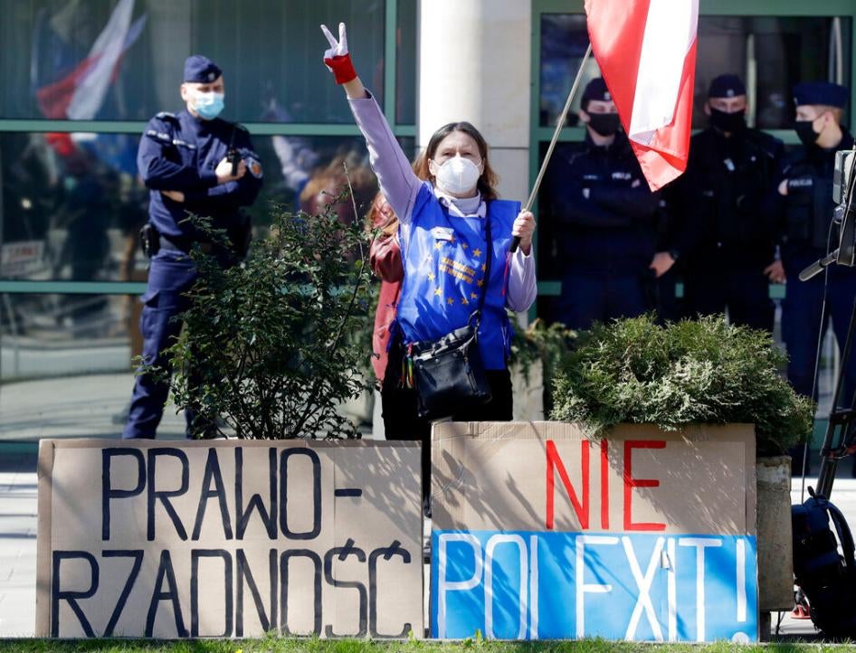 A pro-EU protestor stands outside the Constitutional Tribunal in Warsaw, Poland, on April 28, 2021 with posters that say Rule of Law and No Polexit! 