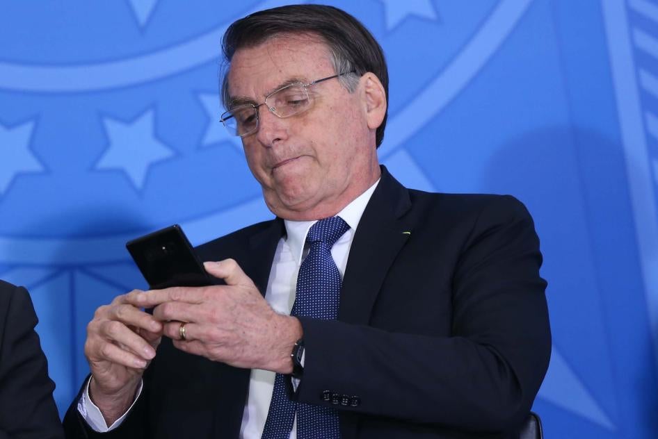Brazil’s President Jair Bolsonaro uses his cellphone during at event at the presidential palace in Brasilia on June 13, 2019. 