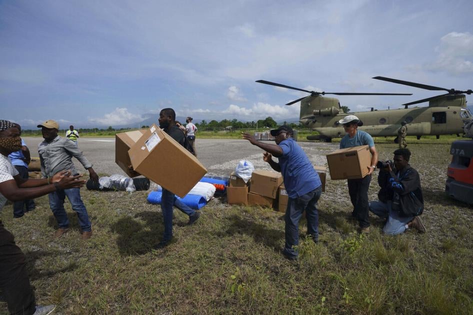 Des résidents locaux et des représentants de l’organisation humanitaire américaine Team Rubicon transportaient des colis livrés par un hélicoptère de l'armée américaine à l’aéroport régional des Cayes, dans l’ouest d’Haïti, le 19 août 2021, cinq jours après le tremblement de terre du 14 août.  