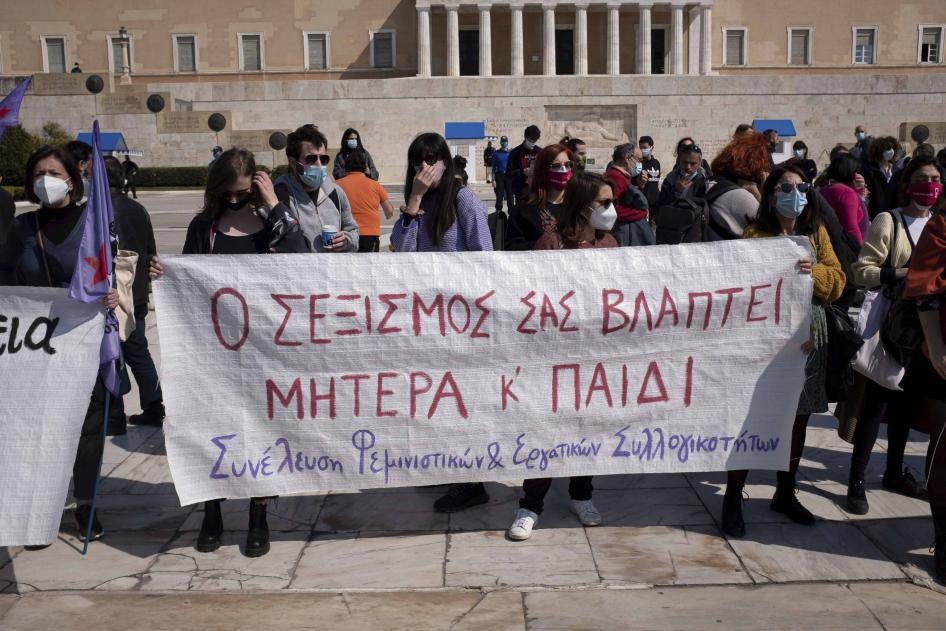 Protesters in Athens, Greece on March 27, 2021 stand outside the Greek Parliament displaying a banner that reads “your sexism is harming both mother and child” against a new law that introduces presumptive co-custody of children, even in cases of domestic violence.