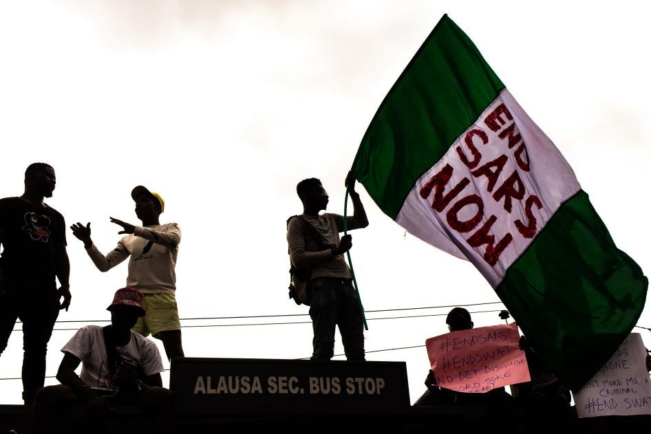 #EndSARS protesters hold up signs, including a Nigerian flag with a message calling for the disbandment of the abusive police unit, during protests on October 15, 2020 in Alausa Lagos, Nigeria. 