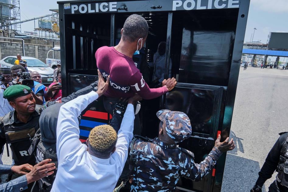Policemen pushing a protestor into a police van during a demonstration on February 13, 2021 in Lagos Nigeria against the re-opening of the Lekki toll gate, where security forces shot at #EndSARS protesters in October 2020. 