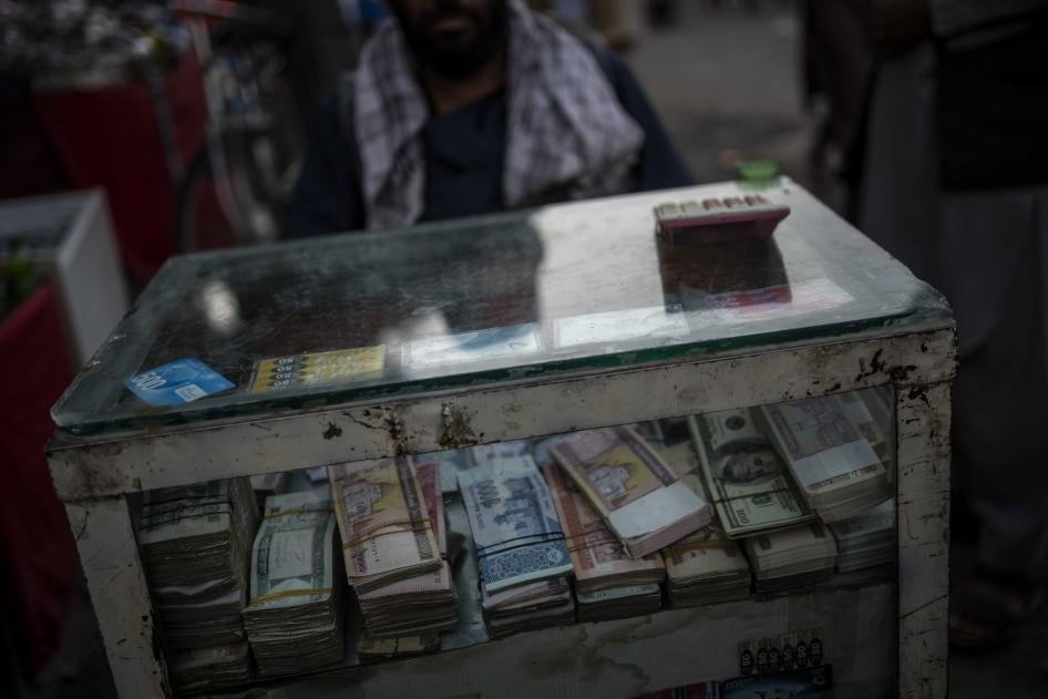 Uma pessoa sentada atrás de uma caixa com dinheiro a espera por clientes que precisem realizar câmbio na cidade velha de Cabul, Afeganistão, 14 de setembro de 2021. 