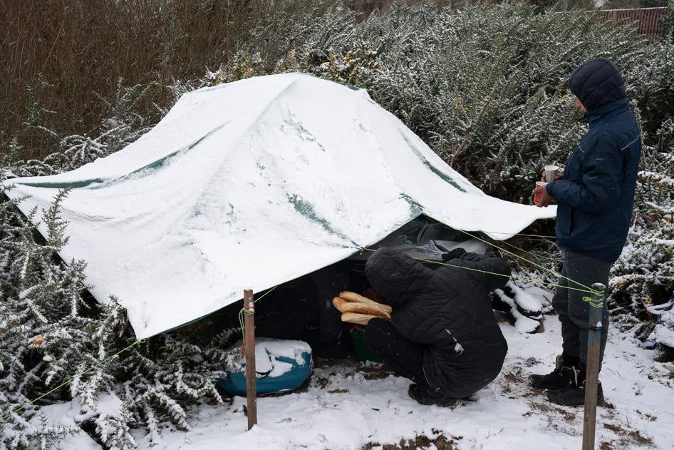 Des bénévoles distribuent de la nourriture et du thé à un groupe de garçons afghans dans un campement de migrants à Calais (nord de la France) en février 2021. 