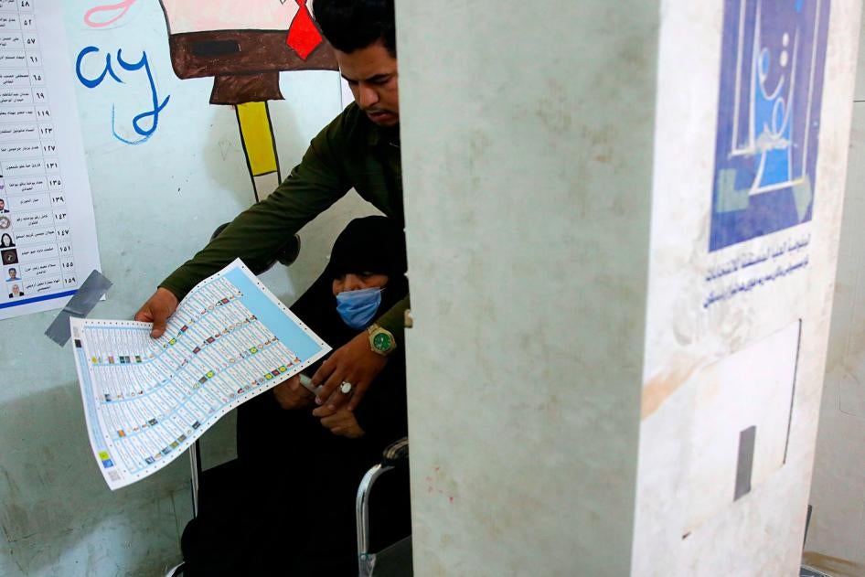 A man helps his mother as she casts her ballot during the parliamentary elections in Basra, Iraq on October 10, 2021.