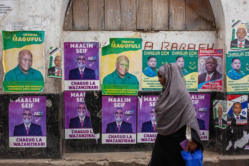 A woman walks past a wall with posters of presidential candidates in Zanzibar’s town on October 24, 2020