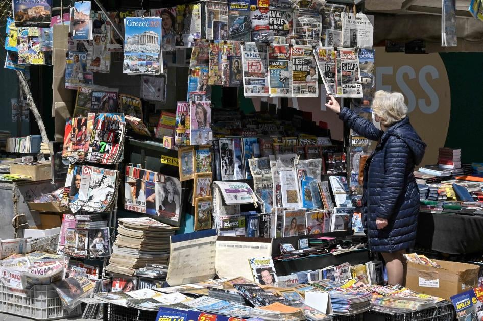 Μία γυναίκα διαβάσει τους τίτλους των εφημερίδων που αναφέρονται στη δολοφονία ενός Έλληνα δημοσιογράφου στις 10 Απριλίου του 2021.