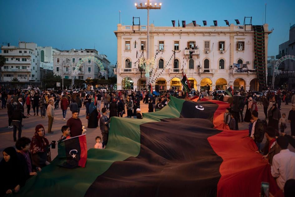 Des personnes portent un drapeau libyen sur la place des Martyrs lors d'une marche commémorant l'anniversaire des manifestations à Tripoli, en Libye, le 25 février 2020.