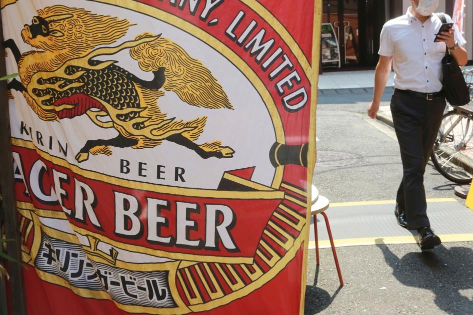 A man walks near an advertisement for a Kirin brand beer in Tokyo, Japan