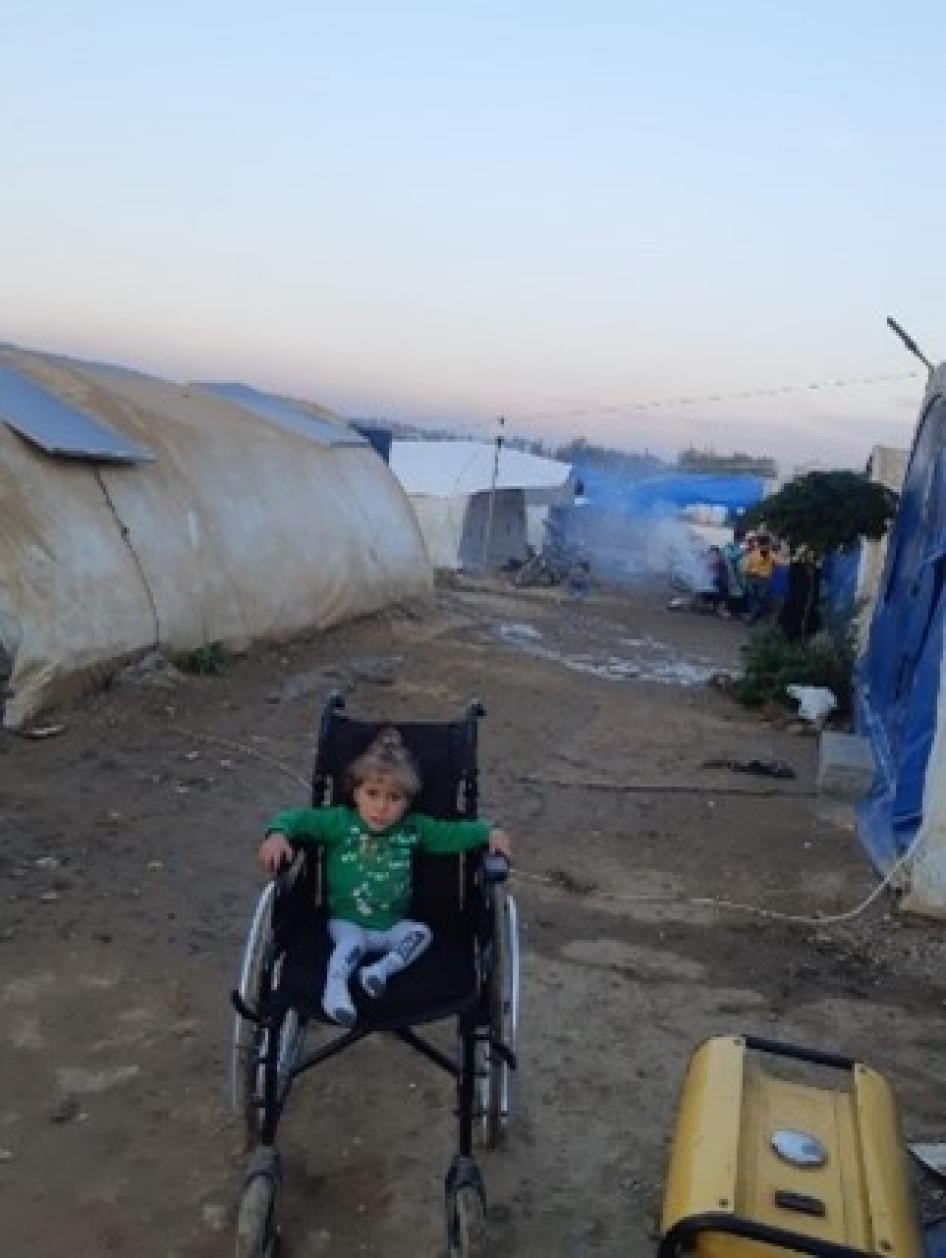 Alaa, 5-year-old girl with a physical disability, sits in an adult wheelchair in the makeshift camp where she lives with her family.