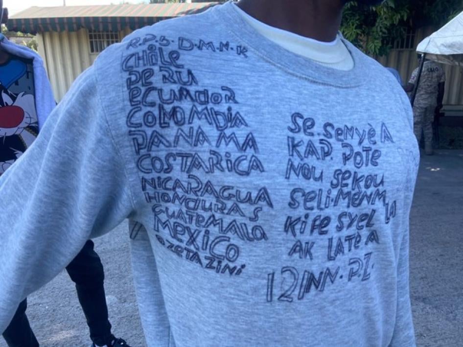 A Haitian who was returned to Haiti from the United States in December 2021 wrote on a sweatshirt the countries he had crossed to get to the US, starting in the Dominican Republic. The writing on the right says, in Creole, “This is the Lord who is rescuing us, he is the one who created heaven and earth.”