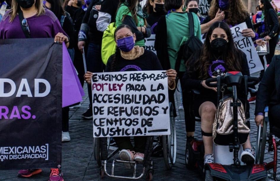 n grupo de mujeres con Discapacidad sostiene un letrero