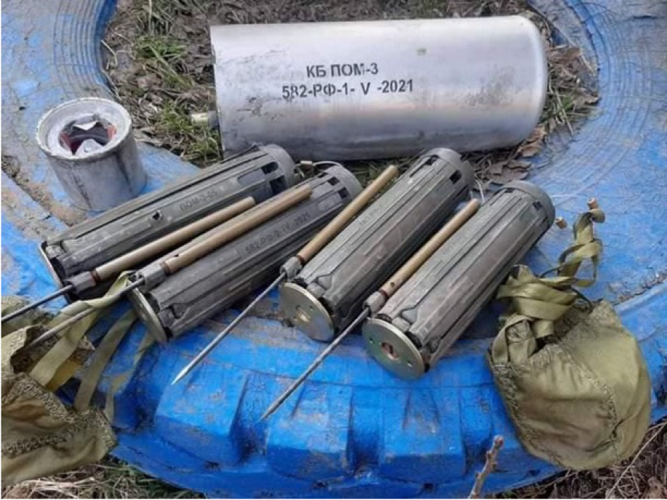 Quatre mines antipersonnel russes POM-3 retrouvées dans la région de Kharkiv, en Ukraine, le 28 mars 2022. Elles ont été désamorcées et posées sur un pneu afin d’être photographiées, près d’un conteneur retrouvé à proximité. Sur deux mines, l’on aperçoit deux petits parachutes censés ralentir leur descente vers le sol après leur largage par le conteneur.