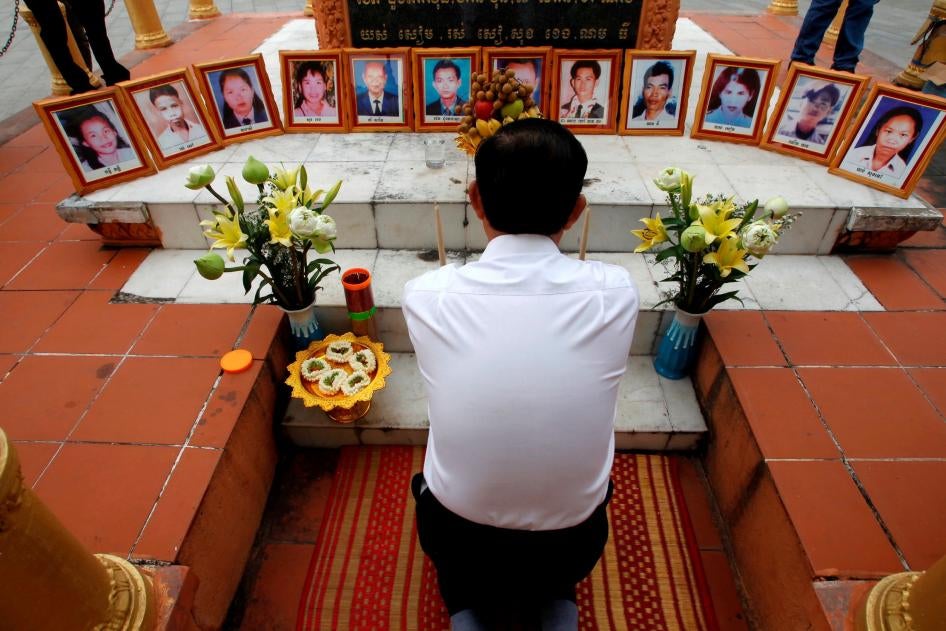 A former opposition party Cambodia National Rescue Party (CNRP) member prays in front of portraits of victims of the March 30, 1997 deadly grenade attack, during a Buddhist ceremony, in Phnom Penh, Cambodia, Friday, March 30, 2018.