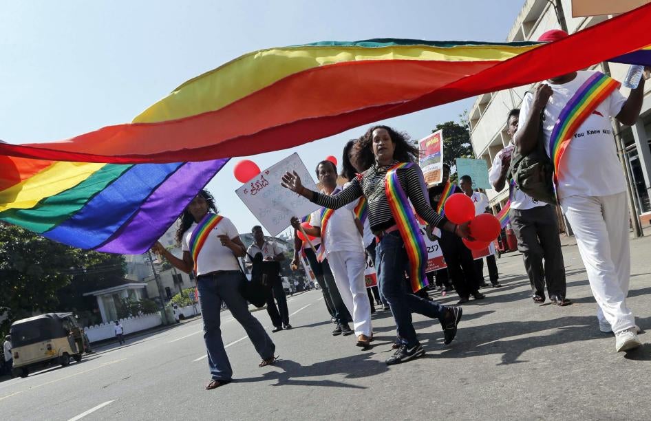 Activists march under a large rainbow flag