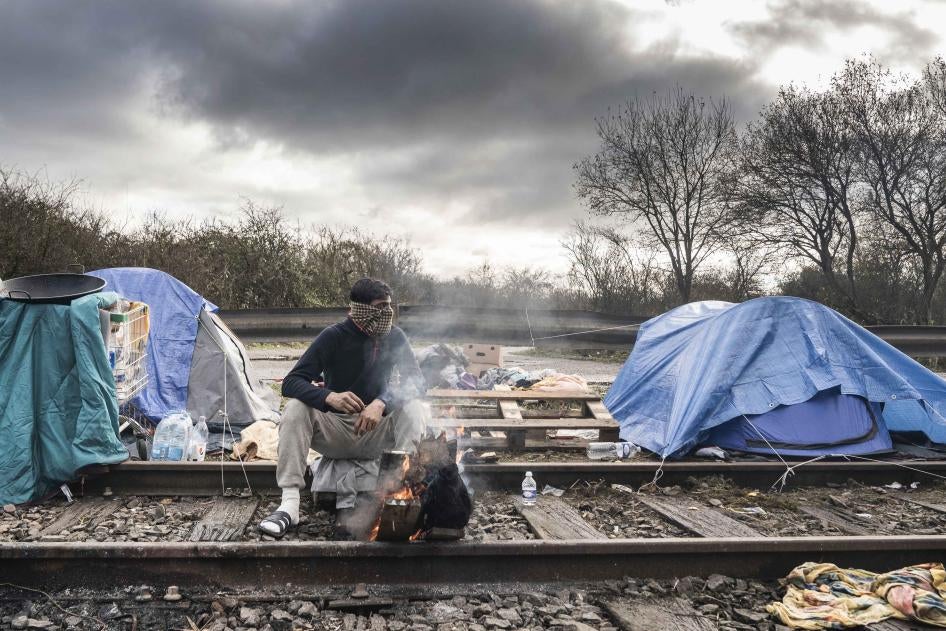 Un migrant se réchauffe en brûlant du bois de chauffage dans un camp de migrants improvisé dans la région de Dunkerque, dans le nord de la France