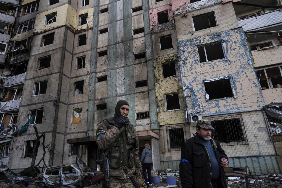Un soldat ukrainien et un homme marchaient devant un bâtiment partiellement détruit par une frappe russe dans le quartier de Satoya à Kiev, en Ukraine, le 20 mars 2022. 