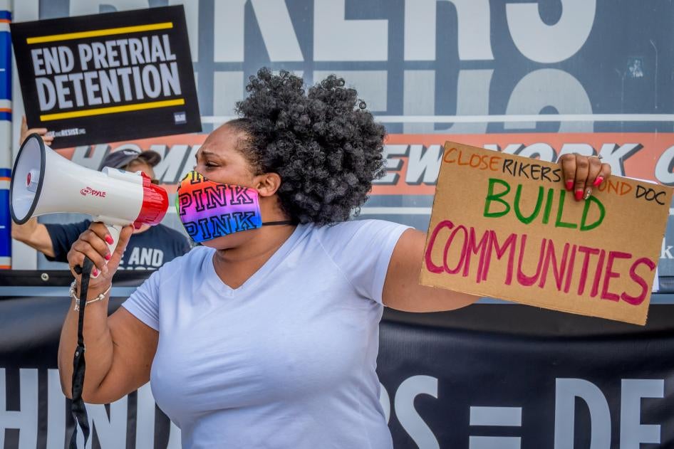 A participant holds a “Build Communities” sign at a rally on Rikers Island in New York, NY. 