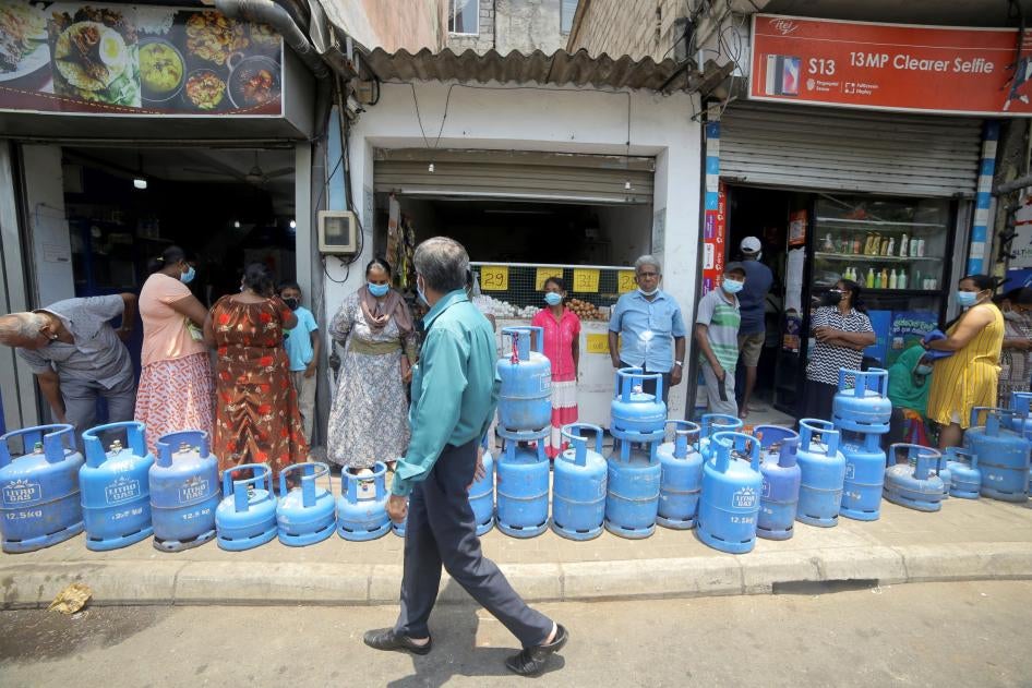 Sri Lankans wearing facemasks wait in line with their empty gas cylinders near a gas shop at Colombo, Sri Lanka, April 1, 2022.