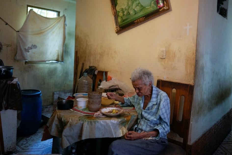 An older woman eats alone in her home