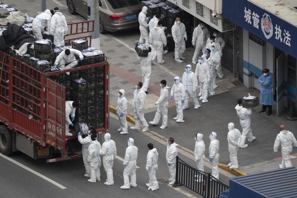 新冠疫情封城期間，穿著白色防疫服的人員從卡車上卸下物資，準備分發給市民，中國上海，2022年4月5日。