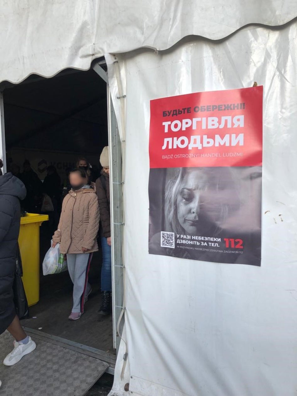 A poster on a humanitarian aid tent at Warsaw's central train station warning refugees about human trafficking and urging them to call the emergency number 112 in case of concern, March 26, 2022