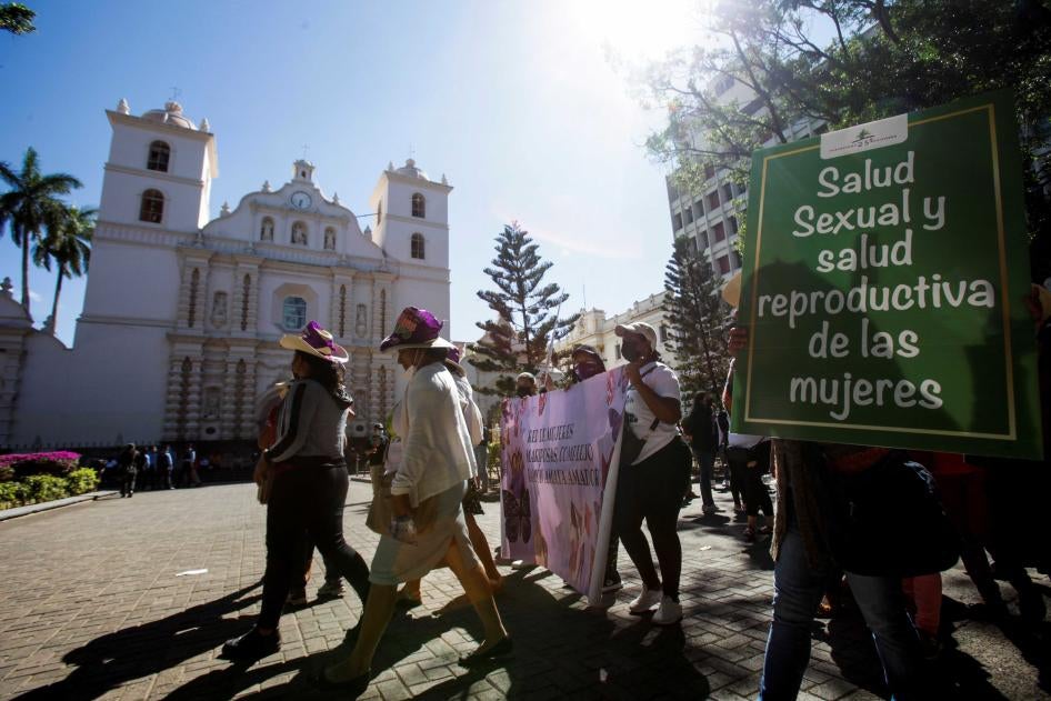Una manifestante lleva un cartel que dice "Salud sexual y salud reproductiva de las mujeres" durante una marcha para conmemorar el derecho al voto y celebrar la elección de la primera mujer presidenta de Honduras, en Tegucigalpa, Honduras, el 25 de enero de 2022.