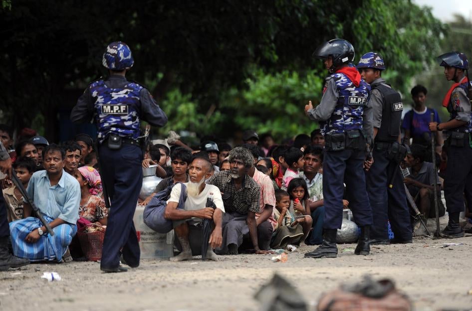 Des policiers du Myanmar, face à des Rohingyas accroupis qui avaient fui leurs maisons lors des violences à Sittwe, le 12 juin 2012.