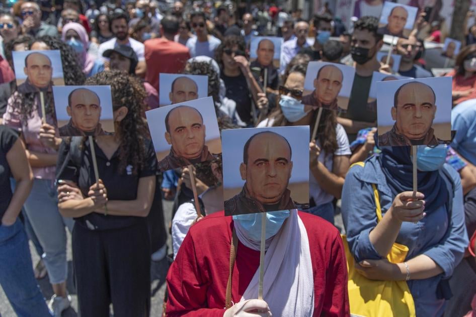 מפגינים נושאים את תמונתו של האקטיביסט ניזאר בנאת במהלך הפגנה בעיר רמאללה שבגדה המערבית ביום שהוכה למוות במשמורת הרשות הפלסטינית, יום חמישי, 24 ביוני 