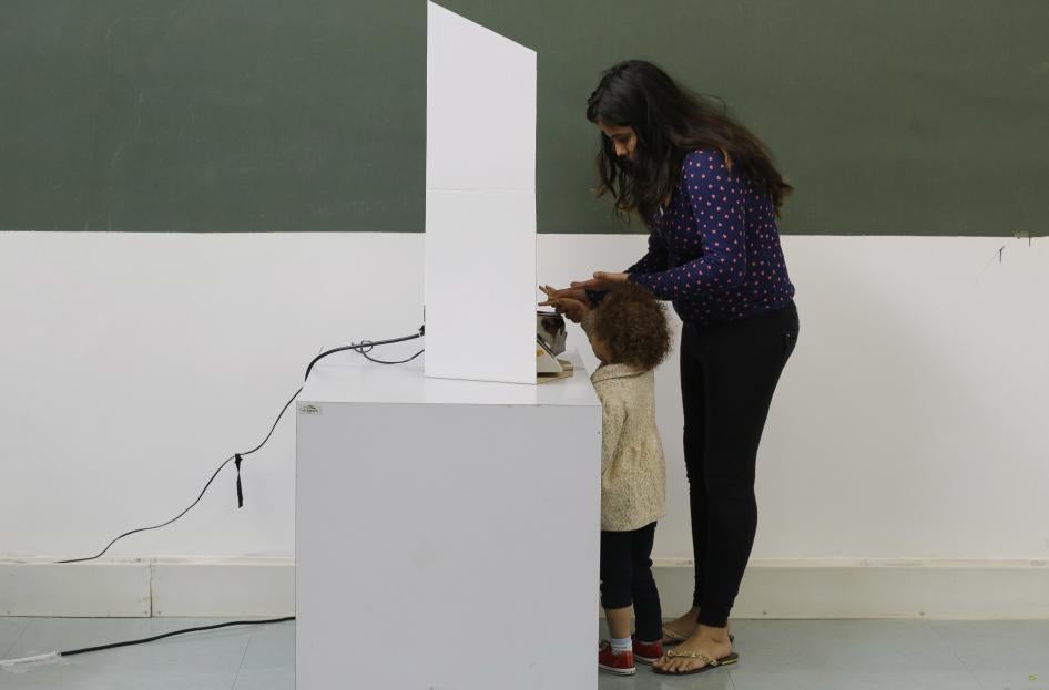 A woman, accompanied by a child, casts her ballot in the municipal election in Sao Paulo, Brazil, Sunday, Oct. 2, 2016.