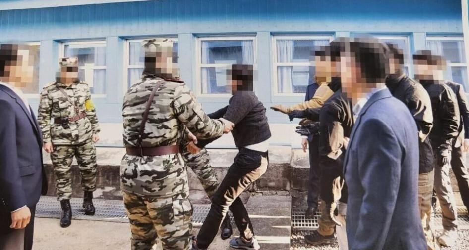Guards drag a man at the border between North and South Korea