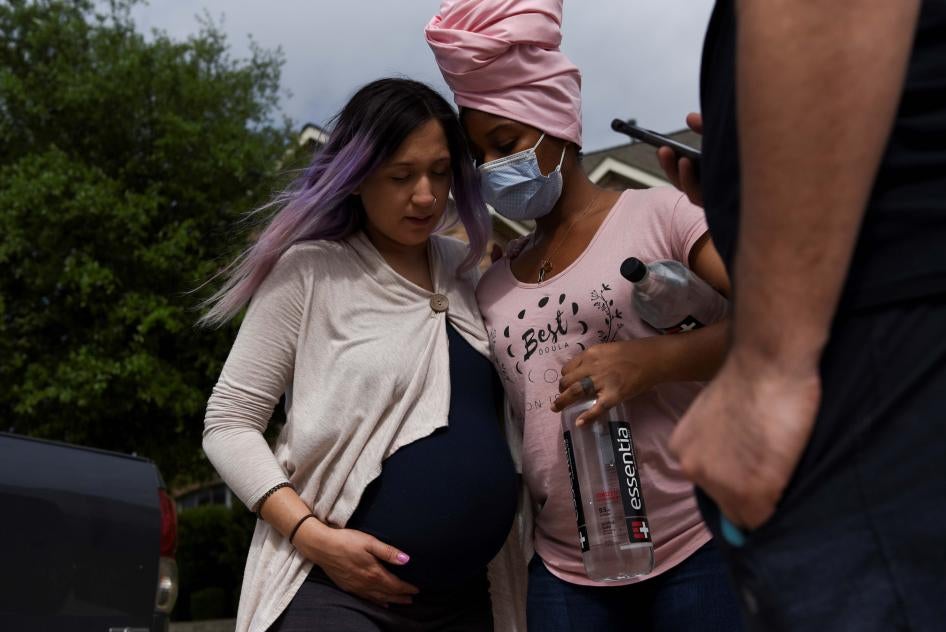 A pregnant woman holds onto another woman