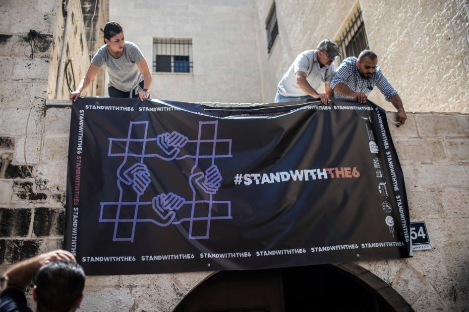 פעילים תולים כרזה לאות הזדהות עם ארגוני חברה אזרחית פלסטיניים שהוצאו מחוץ לחוק במשרדי אחד מהם, ארגון זכויות האדם אל-חק, ב-18 באוגוסט 2022 