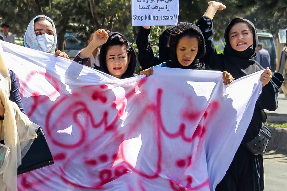 نساء محجبات يتظاهرن مع شعارات في مسيرة. 