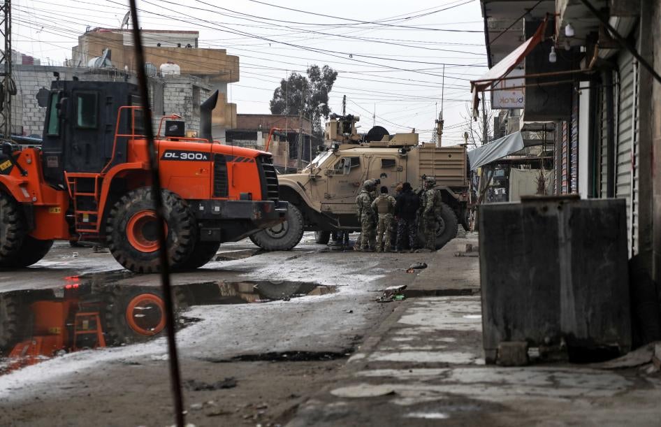 جنود أمريكيون وعناصر في "قوات سوريا الديمقراطية" يقفون بجوار جرافة ومركبات عسكرية في حي غويران شرقي الساعة 2 بعد الظهر في 29 يناير/كانون الثاني 2022.