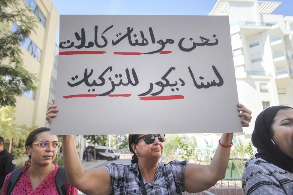 Cette femme tunisienne brandissait une pancarte comprenant l’inscription « Nous sommes des citoyennes à part entière » (en arabe), lors d'une manifestation à Tunis, le 7 octobre 2022. © 2022 Chedly Ben Ibrahim/AP Photo