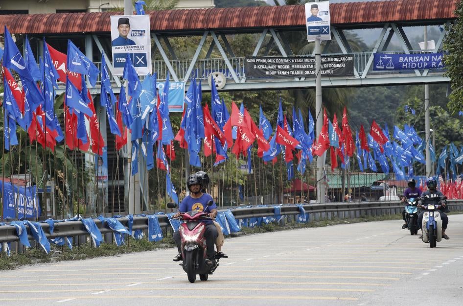 Motorcyclists ride past political party flags in Kuala Lumpur.