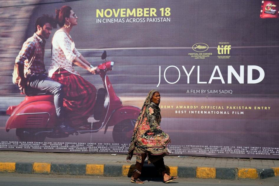 A woman walks past a promotional board for the film "Joyland" in Lahore, Pakistan