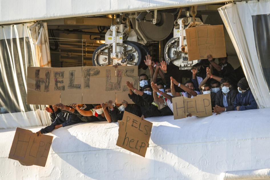 Migrants hold banners asking for help from a deck of the Geo Barents rescue ship operated by Doctors Without Borders, in Catania's port, Sicily, southern Italy, November 7, 2022