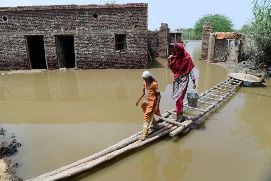 A woman and girl walk on a temporary bamboo path near their flooded house in Shikarpur, Pakistan.