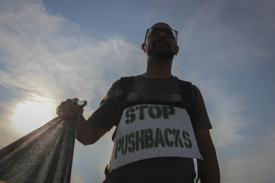 A man holds a banner during a protest against the violent pushbacks of migrants, allegedly conducted by Croatian police, near the border crossing between Croatia and Bosnia and Herzegovina