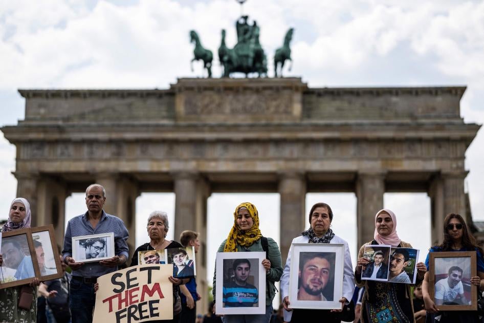 Des proches de Syriens détenus par le gouvernement syrien ou « disparus » tenaient des photos de ces personnes lors d'un rassemblement tenu pour appeler à leur libération, devant la porte de Brandebourg à Berlin, le 7 mai 2022.