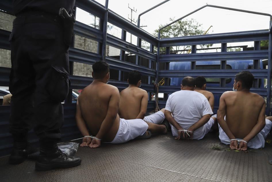 Personas detenidas por la policía esperan con las manos esposadas con amarras en la parte trasera de un camión en la delegación policial de San Bartolo antes de ser trasladas a prision, Sopayango, El Salvador, 16 de agosto de 2022.