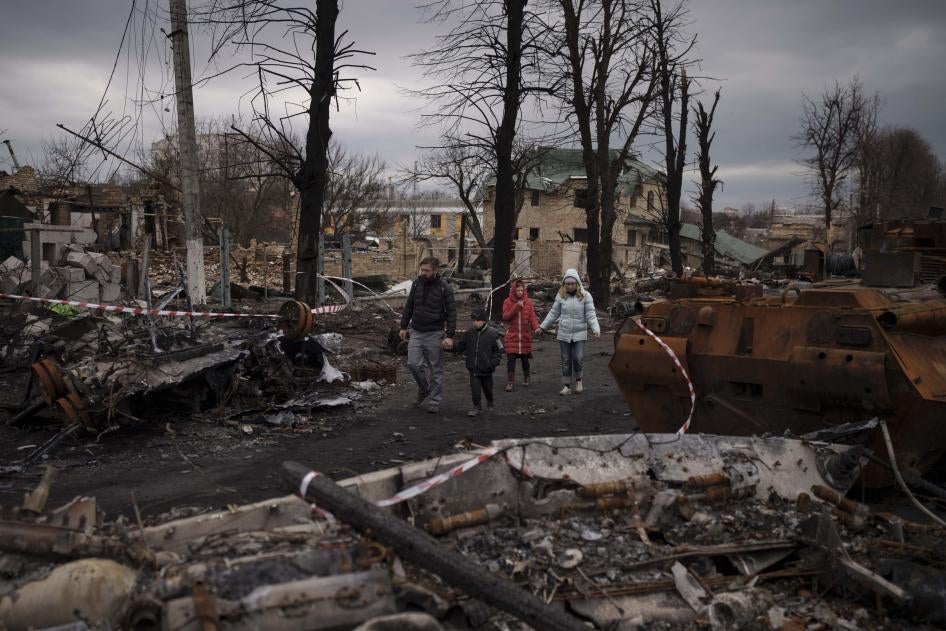 Une famille marche au milieu de véhicules militaires détruits à Boucha, près de Kiev, en Ukraine, le 6 avril 2022. 