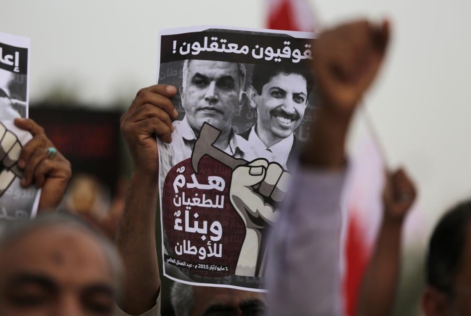 متظاهر بحريني معارض للحكومة يحمل لافتة تدعو إلى الإفراج عن الناشطين الحقوقيين السجينين نبيل رجب (أفرج عنه في 2020)، يسار، وعبد الهادي الخواجة، يمين، في المنامة، البحرين، 1 مايو/أيار 2015.