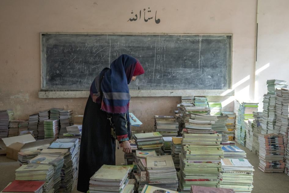 An Afghan teacher collects books in a school in Kabul, Afghanistan.